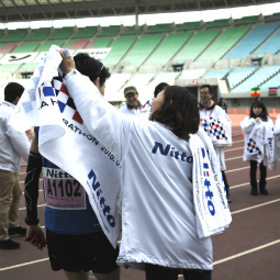 Voluntários distribuindo toalhas aos corredores na Meia Maratona de Osaka