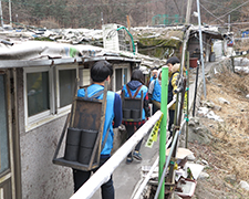Волонтеры по цепочке передают брикеты в узком проходе между домами